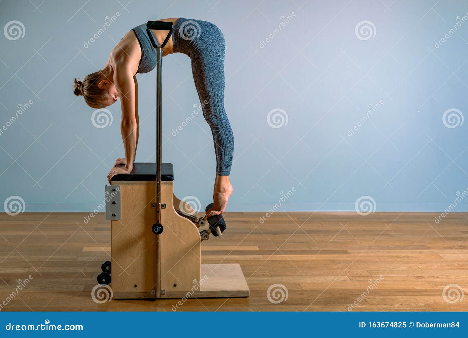 Pilates Woman in a Cadillac Reformer Doing Stretching Exercises in the ...