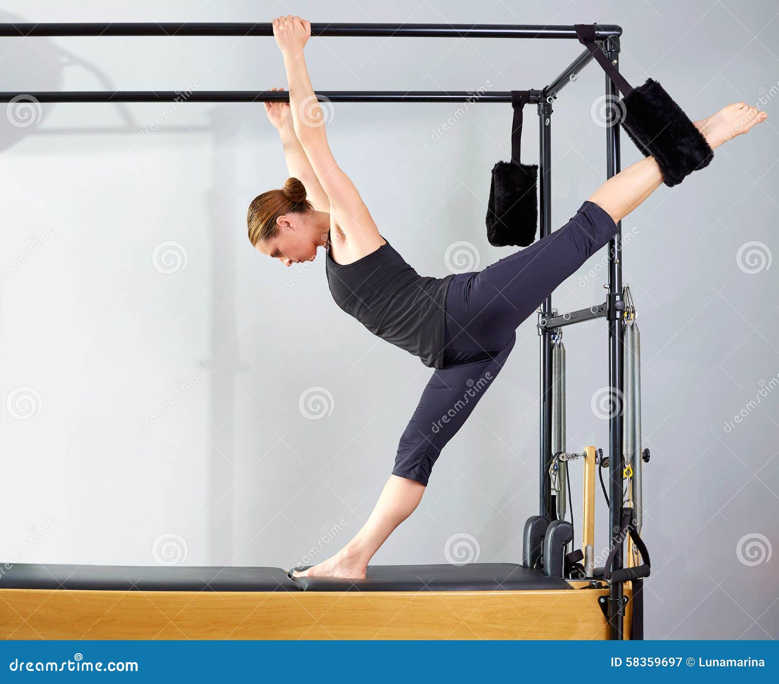 Fit female coach hanging hands and feet from the Pilates machine
