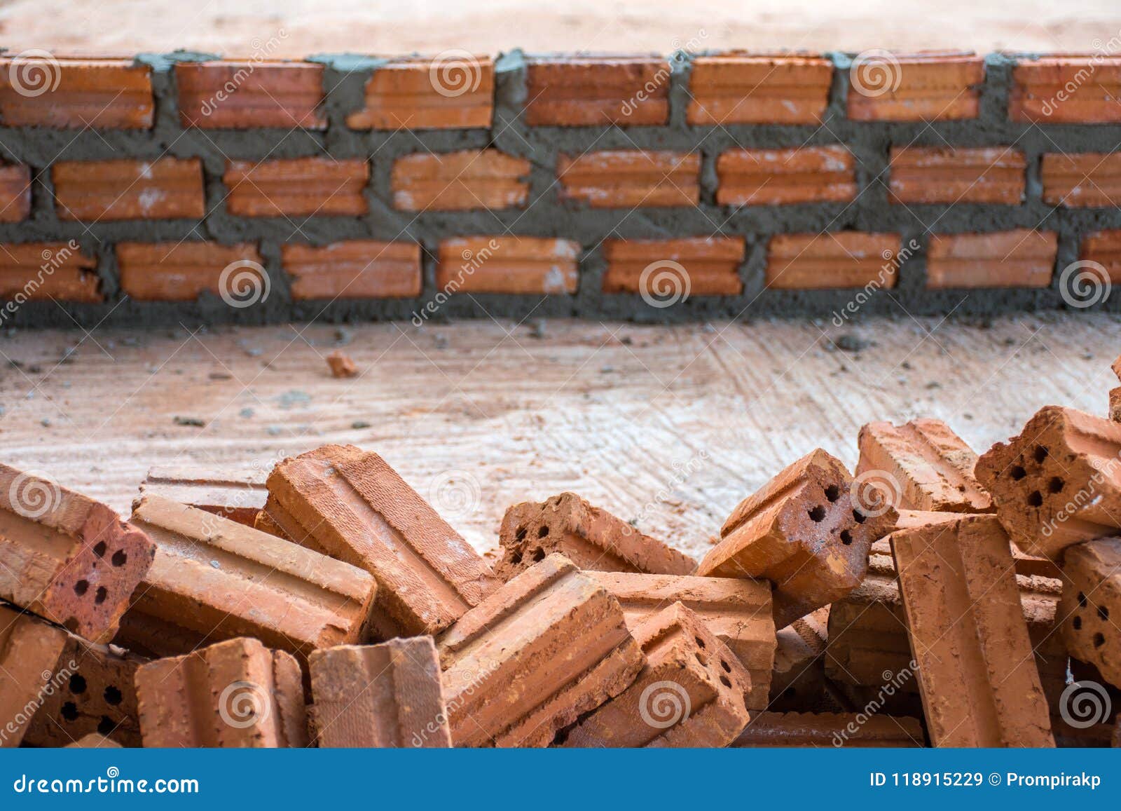 Pile of Bricks in Construction Site with Brick Wall Layer Under Stock