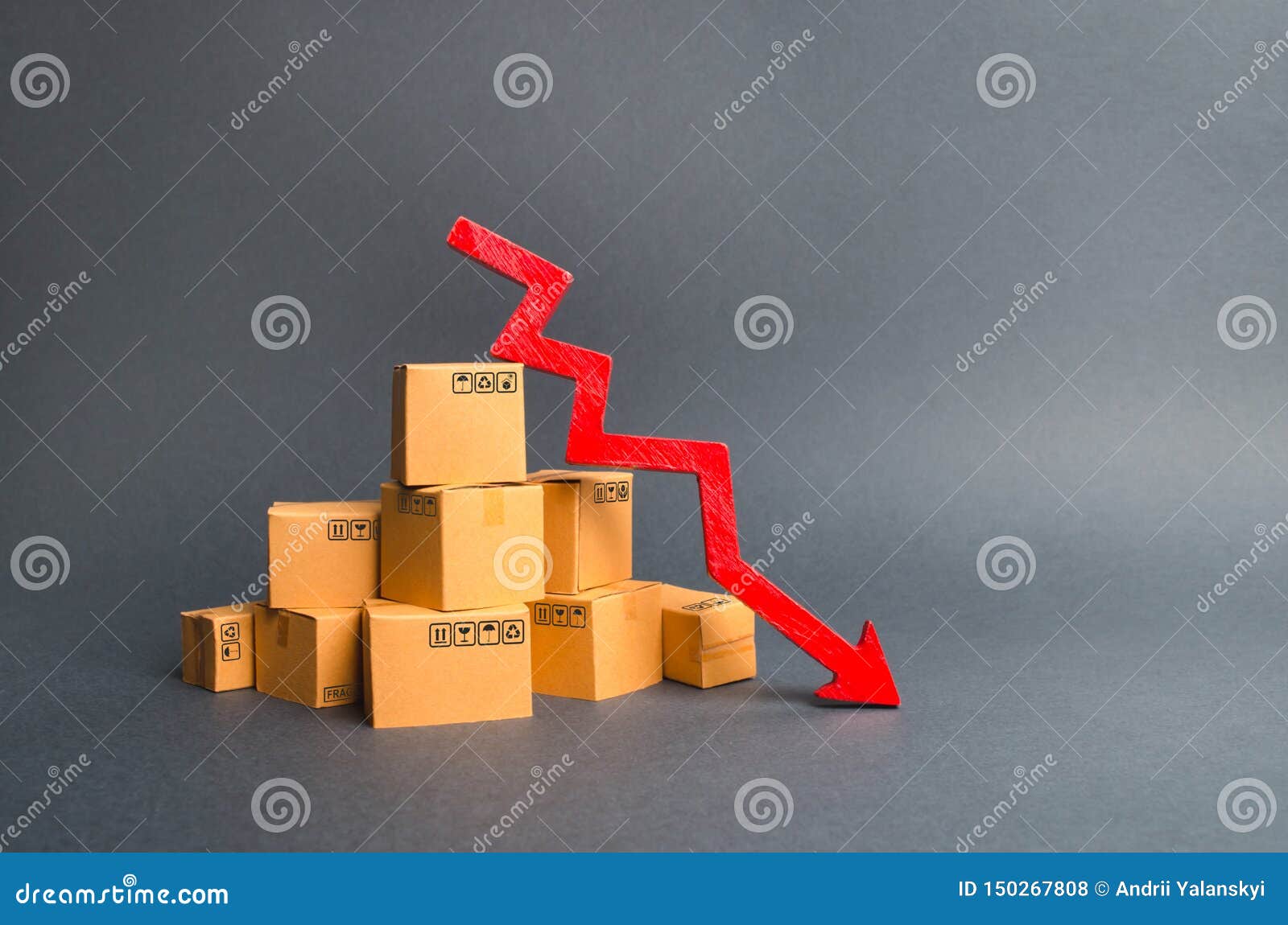 a pile of cardboard boxes and a red arrow down. the decline in the production of goods and products, the economic downturn