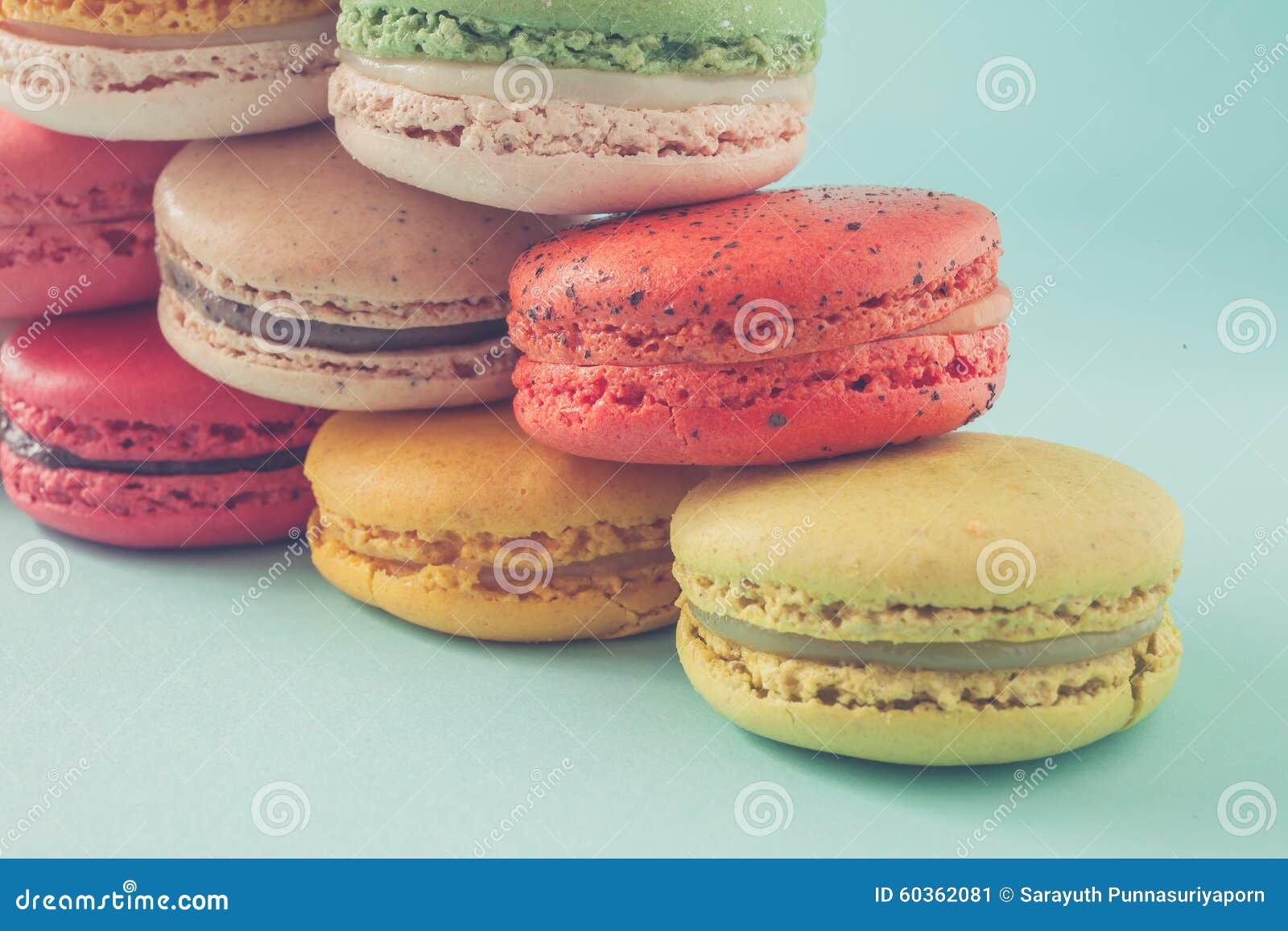 pile of colorful macaroons stacked up like a tower in turquose pastel background (selective focus) - closeup.