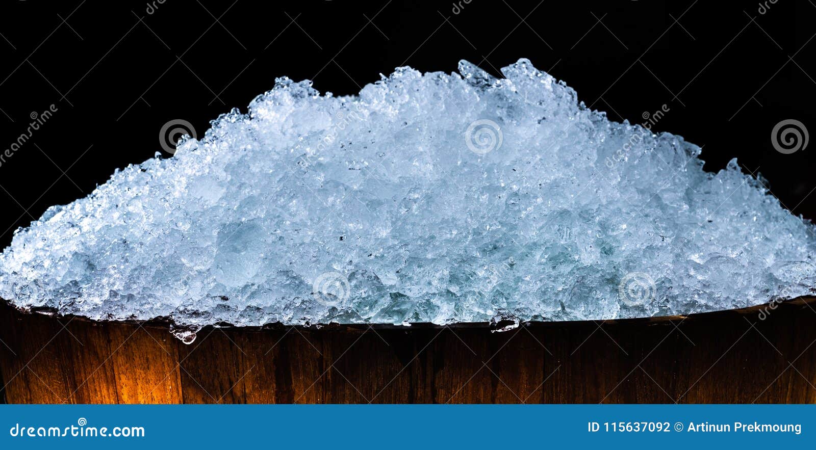 pile of crushed ice cubes in wood bucket on dark background with copy space. crushed ice cubes foreground for beverages, beer