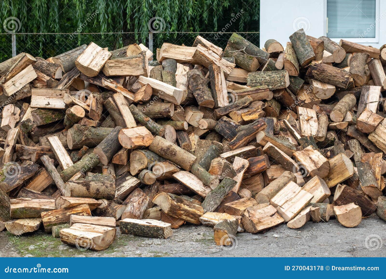 A Pile of Firewood for Heating in Winter in the Yard of the Farm Stock