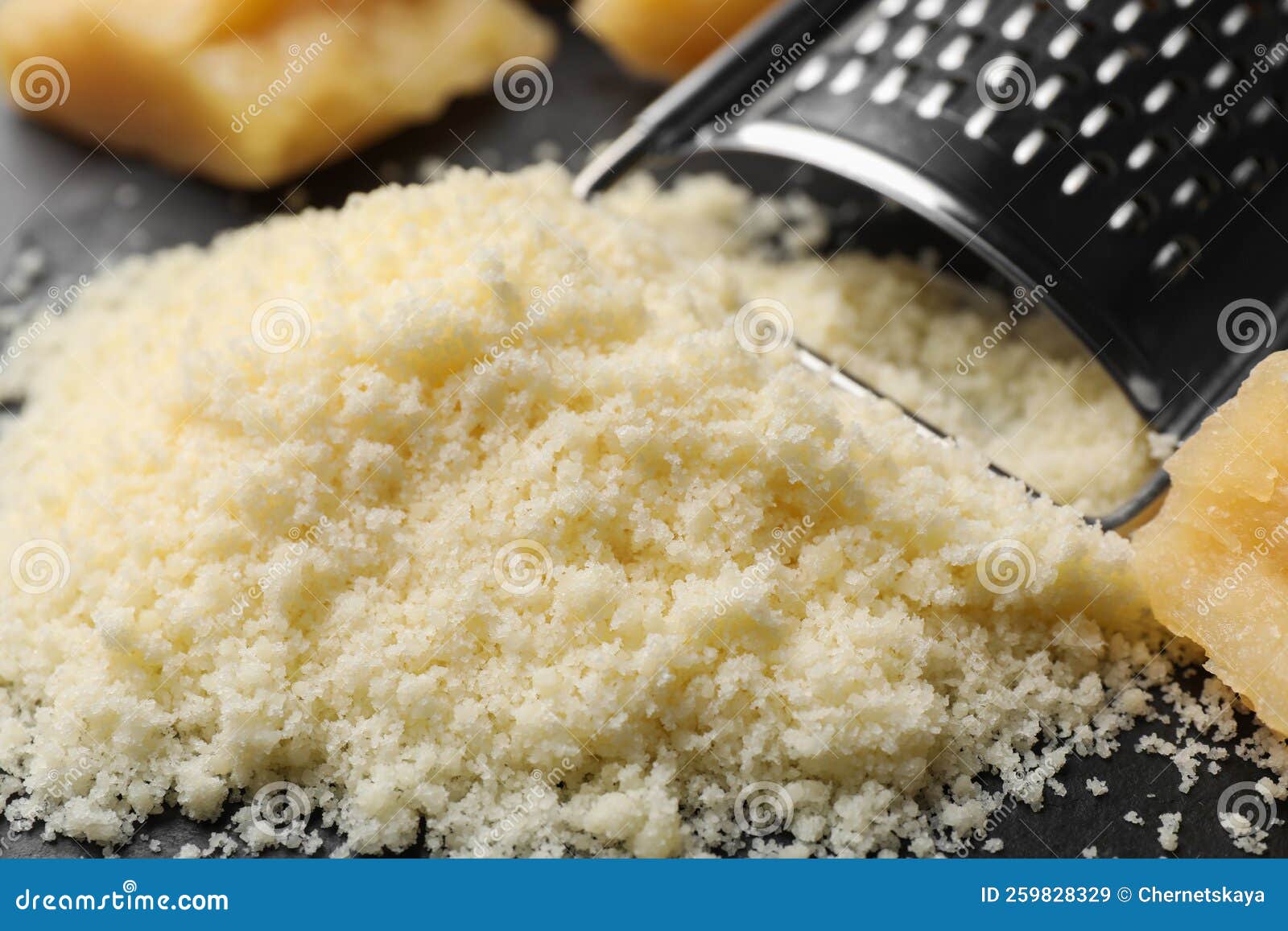 Pile of Grated Parmesan Cheese and Grater on Black Table, Closeup Stock