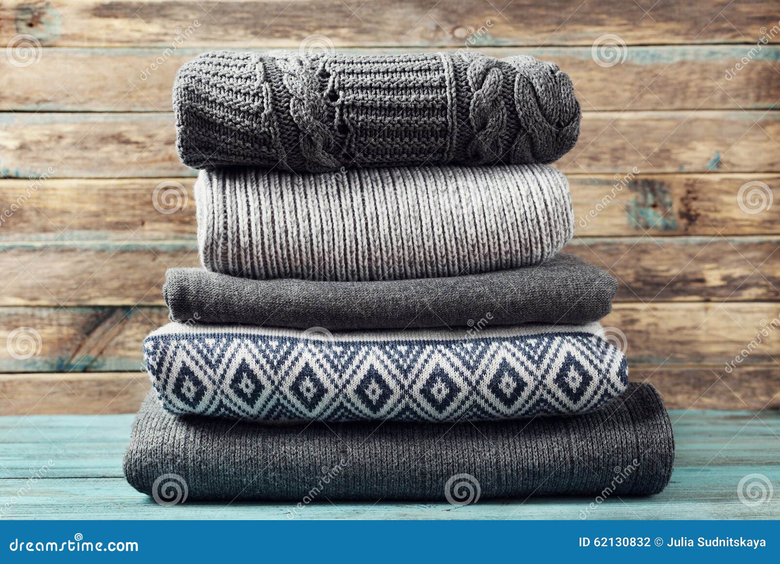 pile of knitted winter clothes on wooden background, sweaters, knitwear