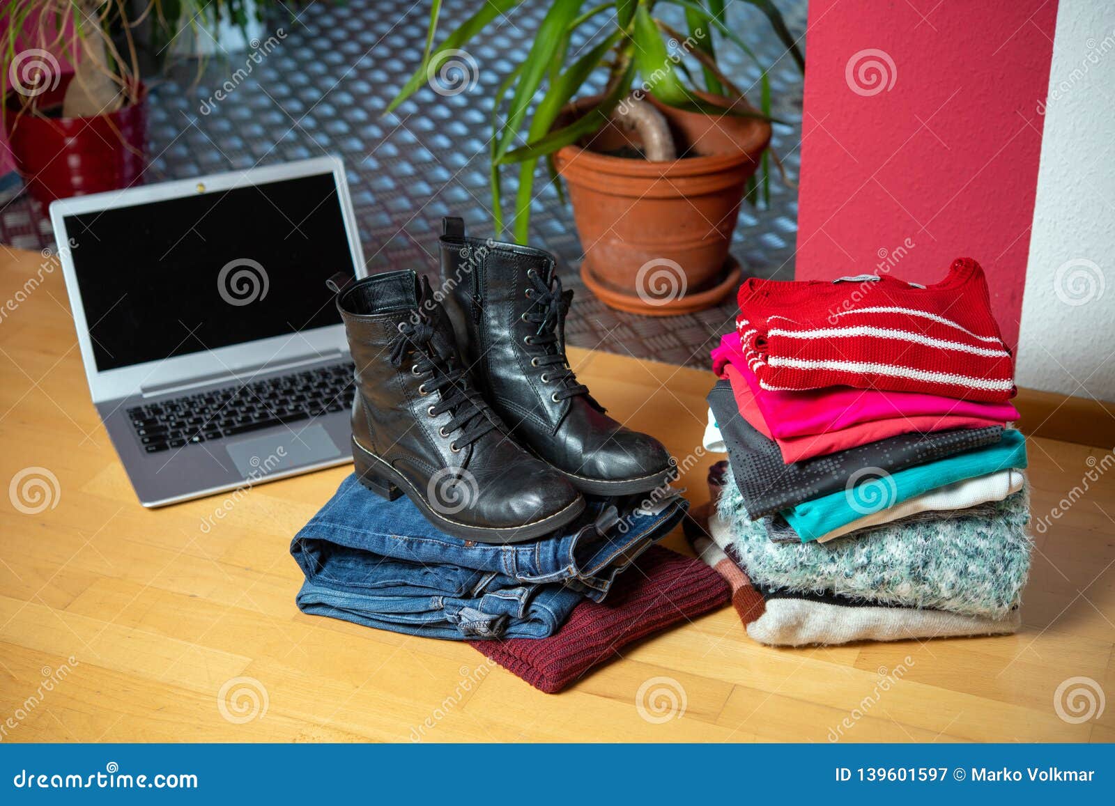 pile of second hand clothing and shoes with computer on floor