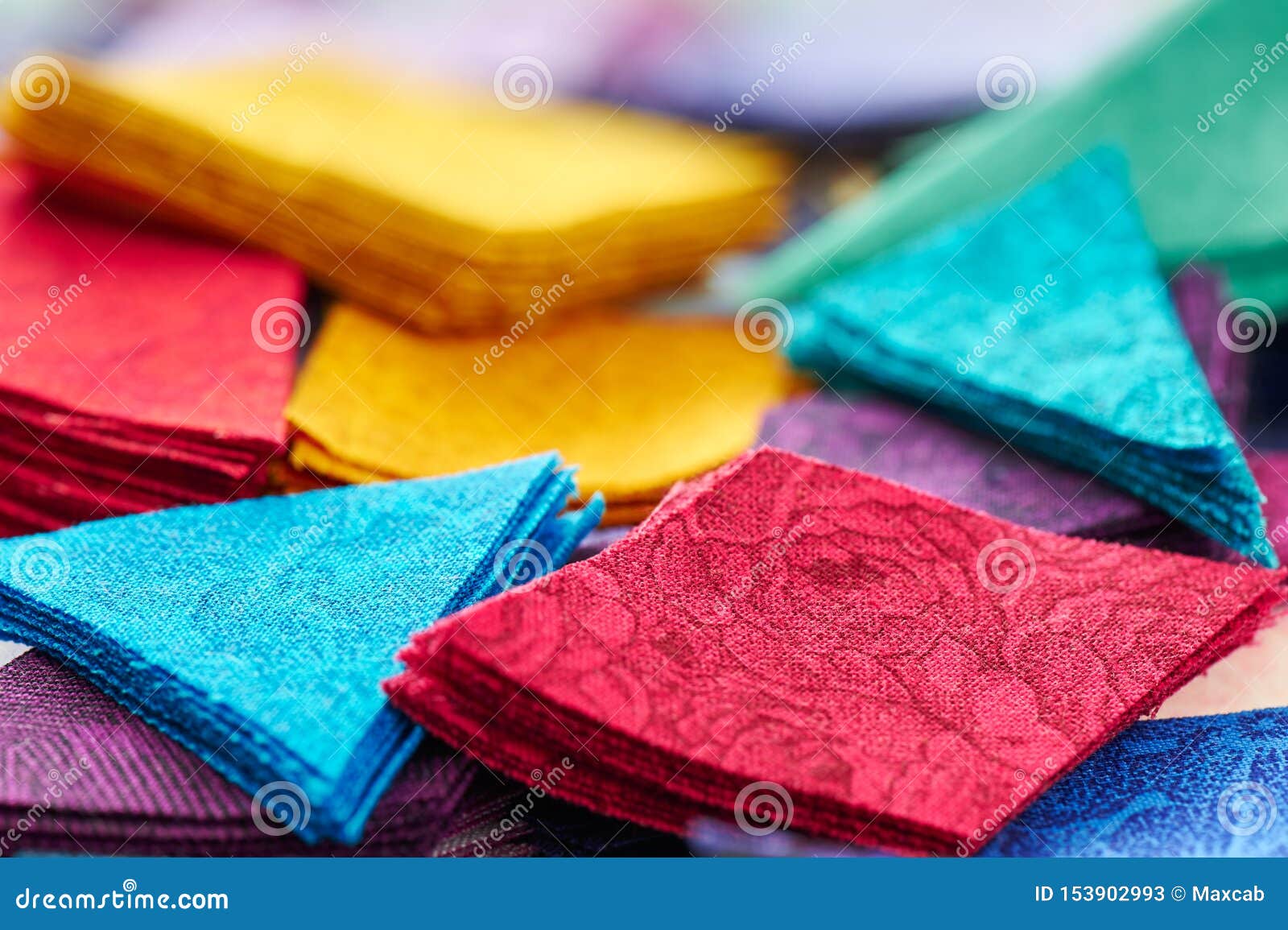 A stack of multi-colored fabric for sewing. Many different fabrics are  stacked on a table. Fabric for sewing clothes and bed linen. Stock Photo