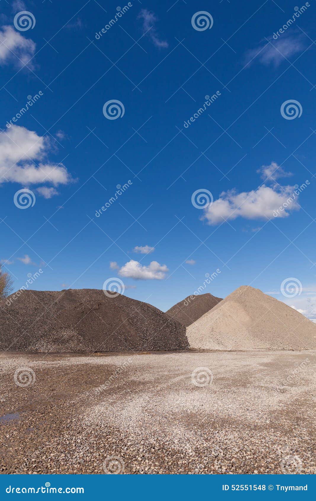 Piles of Gravel at Construction Site Under Bright Blue Sky Stock Photo