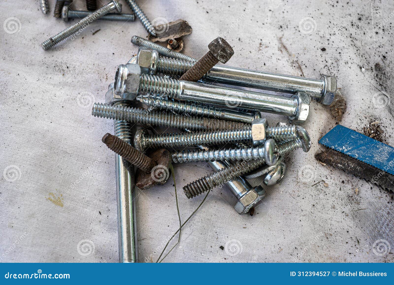 piles of nuts bolts cutting blades and different hardware on a drop sheet