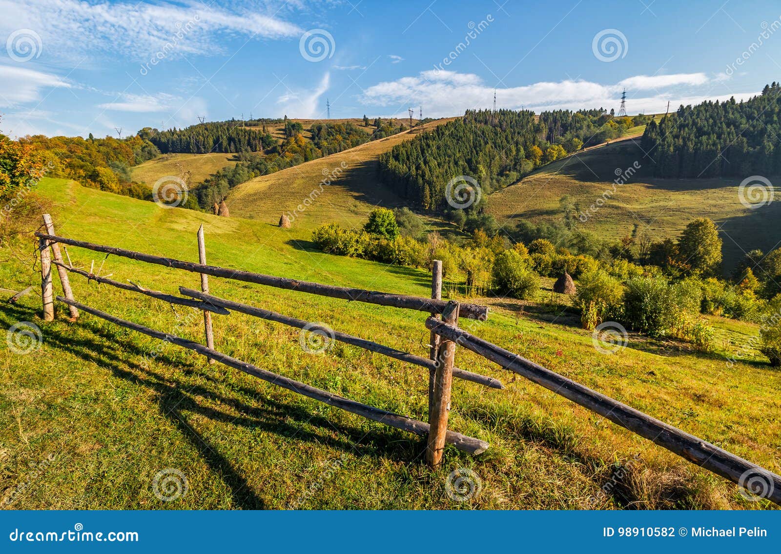 Pilhas do feno atrás da cerca no campo rural paisagem montanhosa Carpathian bonita do campo perto da floresta na manhã adiantada do outono