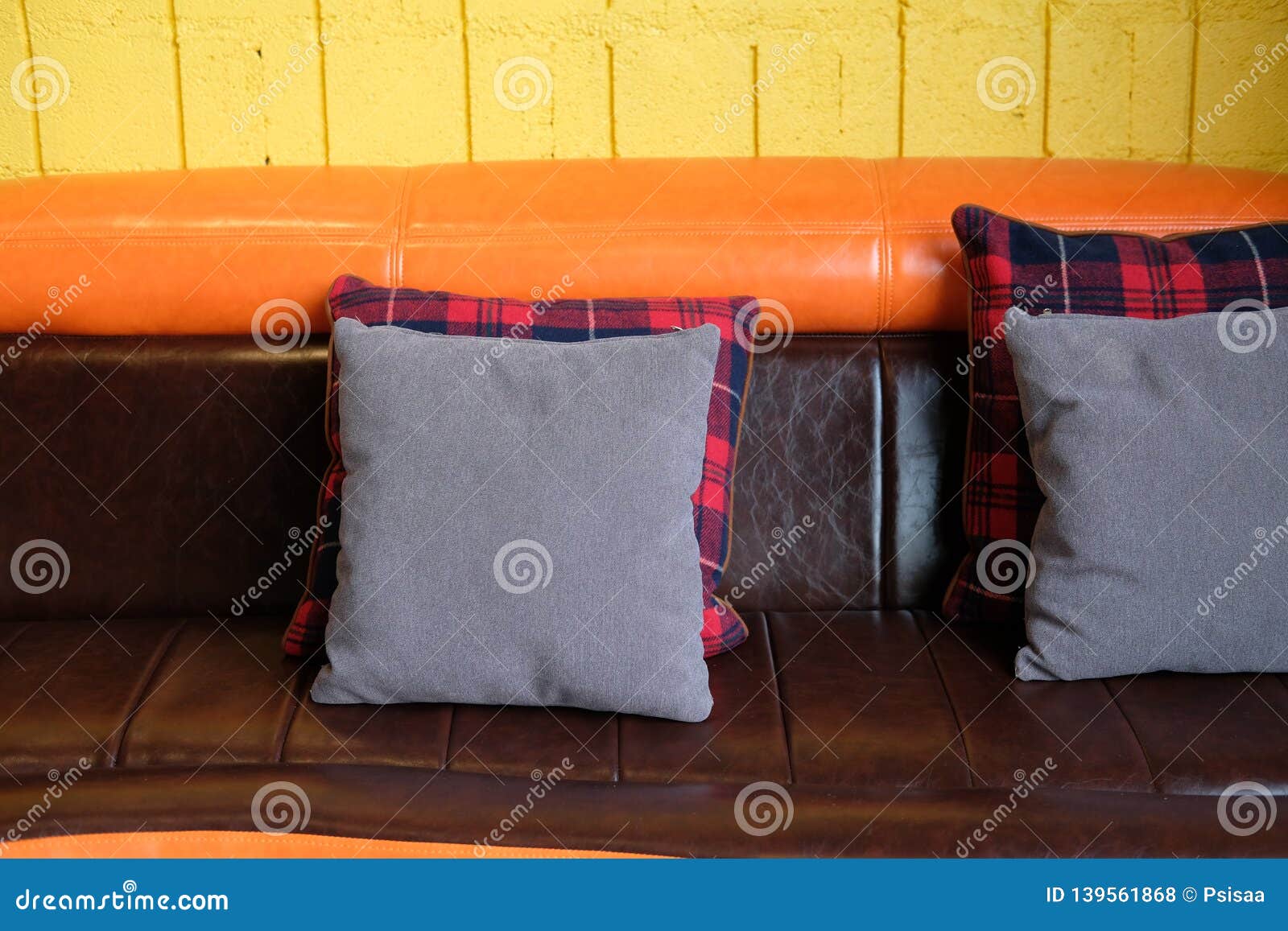 Pillow On Brown Orange Leather Sofa Couch Beside Yellow Wall Stock