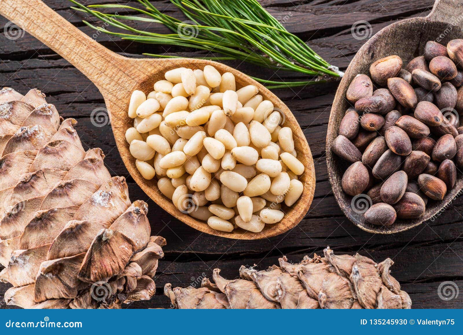 pine nuts in the spoon and pine nut cone on the wooden table. organic food