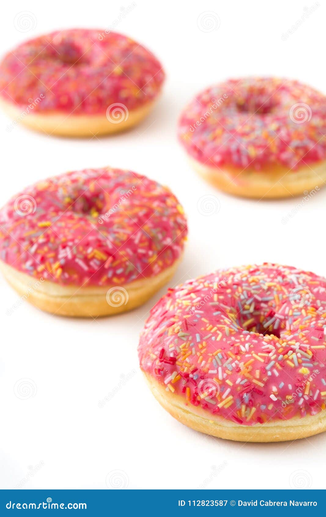 Pink frosted donut with colorful sprinkles isolated on white background.
