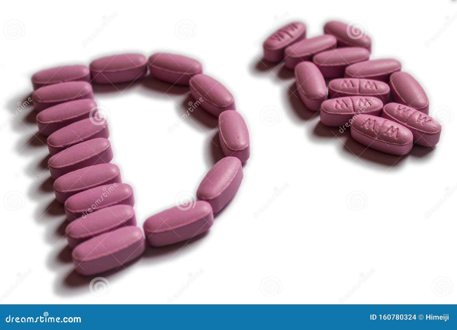 Pink Oval Tablets in a Shape of Letter D Next To Pile of Same Pills