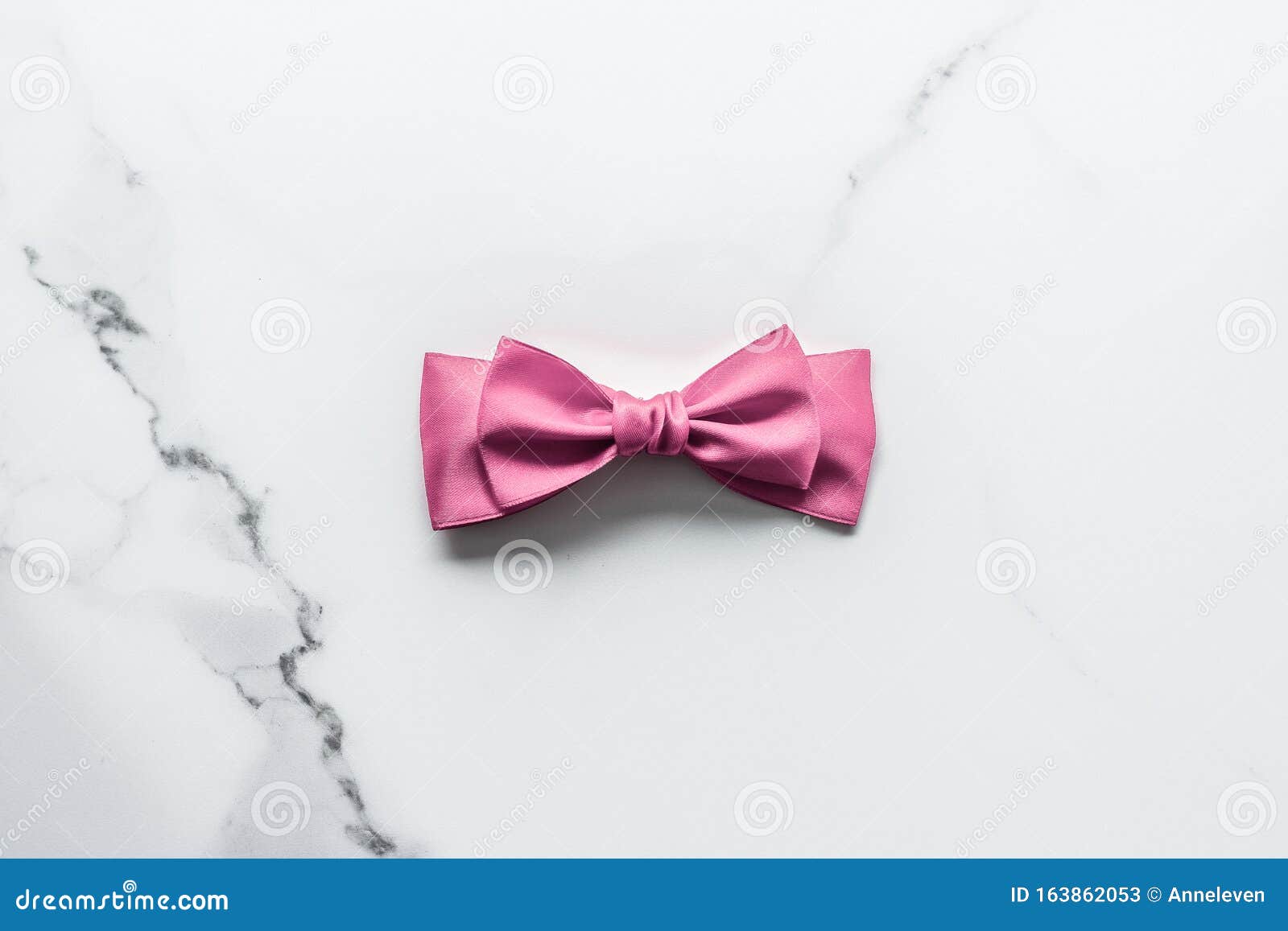 Pink silk ribbon and bow on marble background, girl baby shower