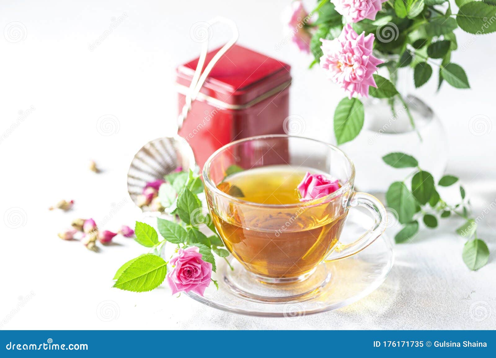 pink tea buds, a glass cup and vintage strainer