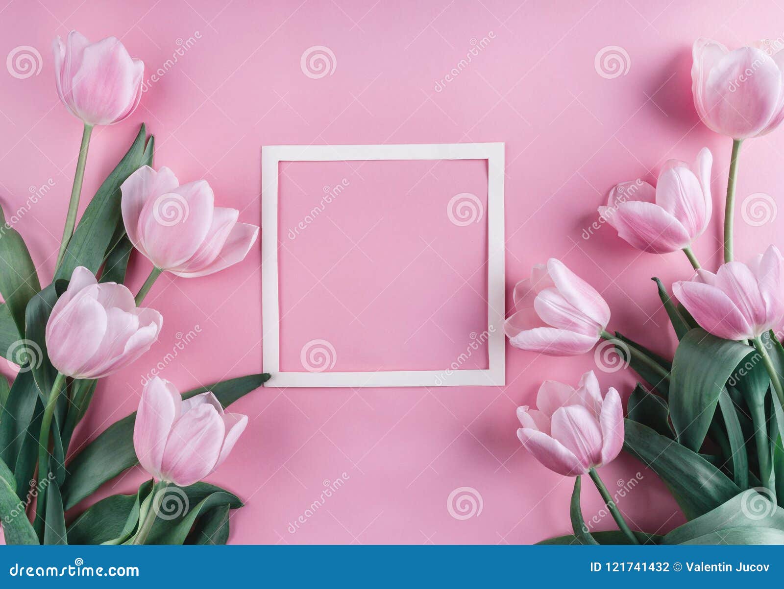pink tulips flowers and sheet of paper over light pink background. saint valentines day frame or background.