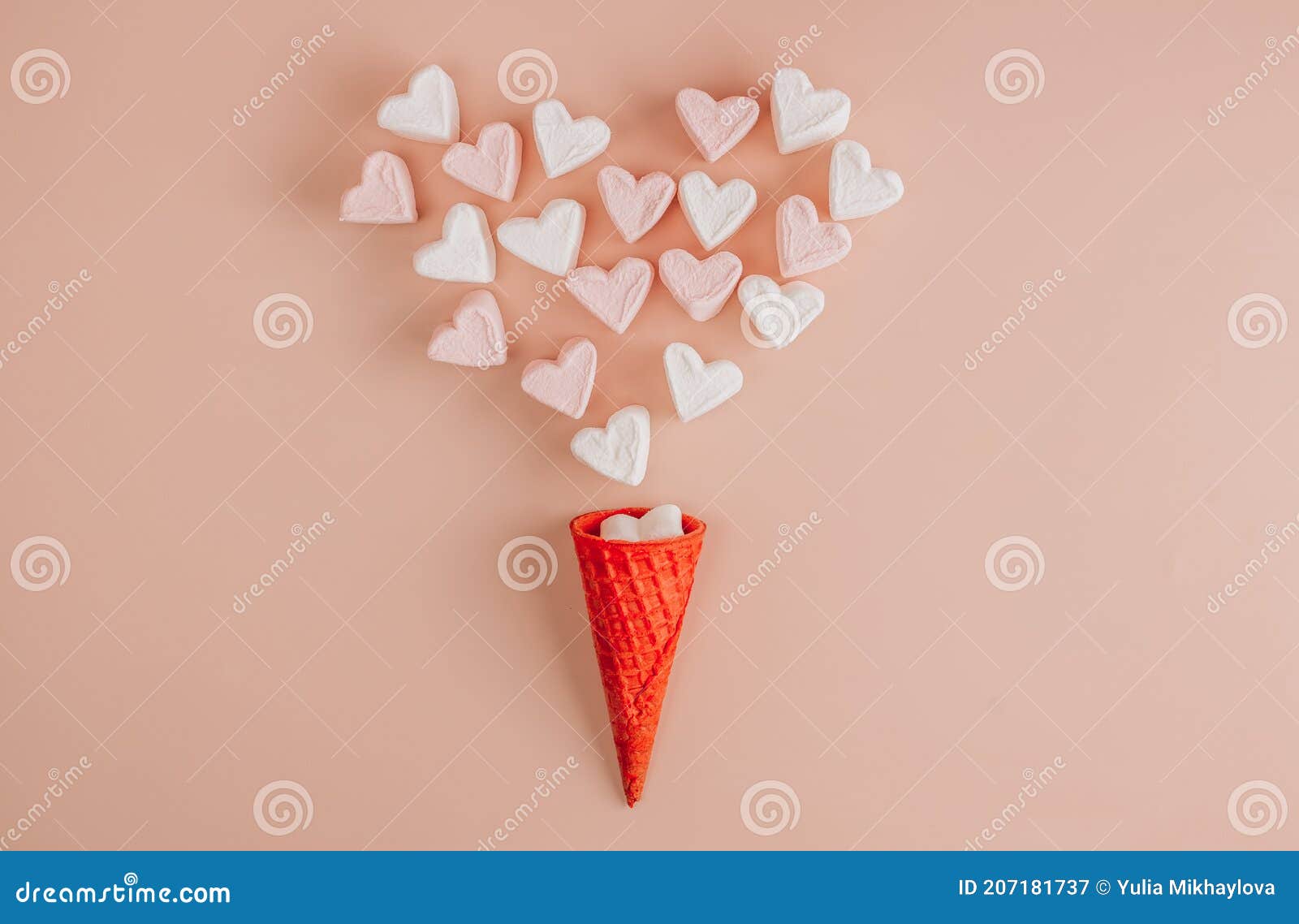 Waffle cone with heart-shaped marshmallows, close-up on a blue