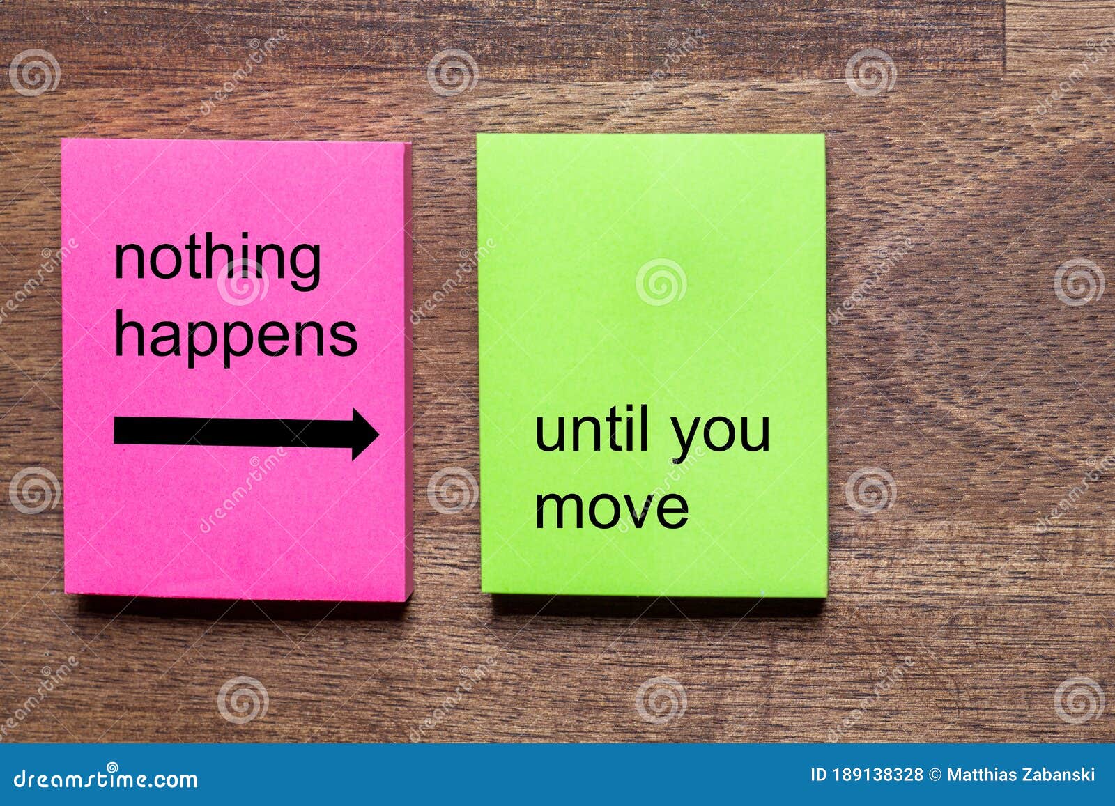 pink and yellow self-adhesive note sticker with the motto: nothing happens until you move. background dark wooden table