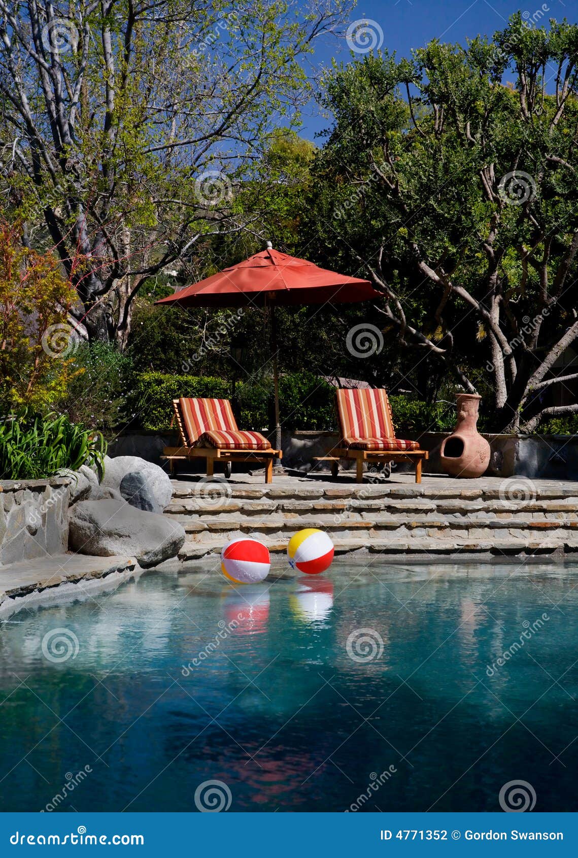 Sillas de cubierta bajo sombrilla por la piscina del estado del patio trasero.