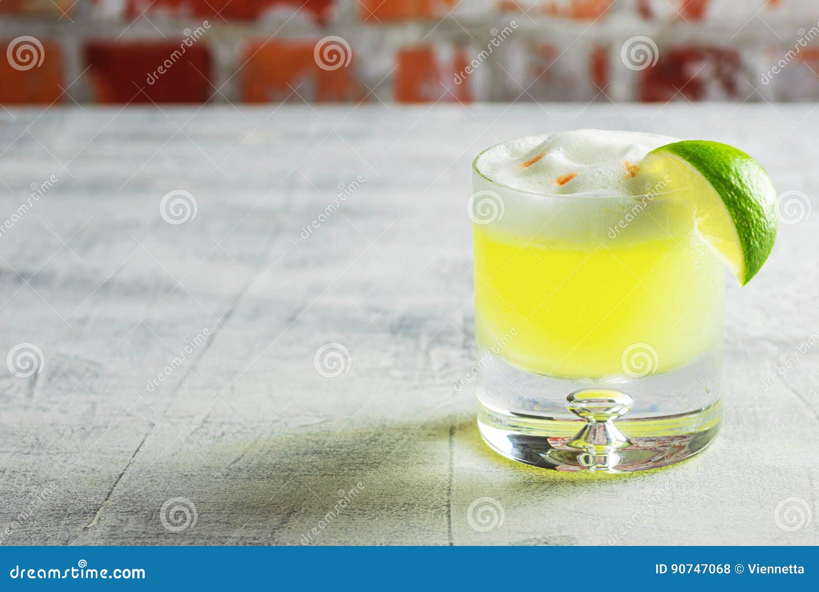 pisco sour cocktail in glass with lime