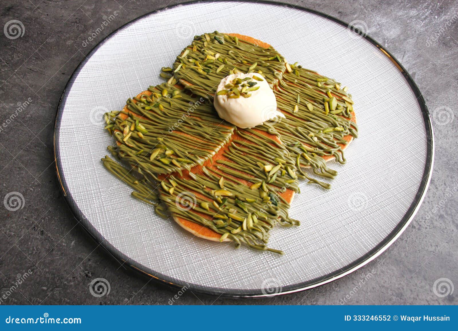 pistachio drizzled pancakes with vanilla ice cream served on a white plate side view of decadent dessert