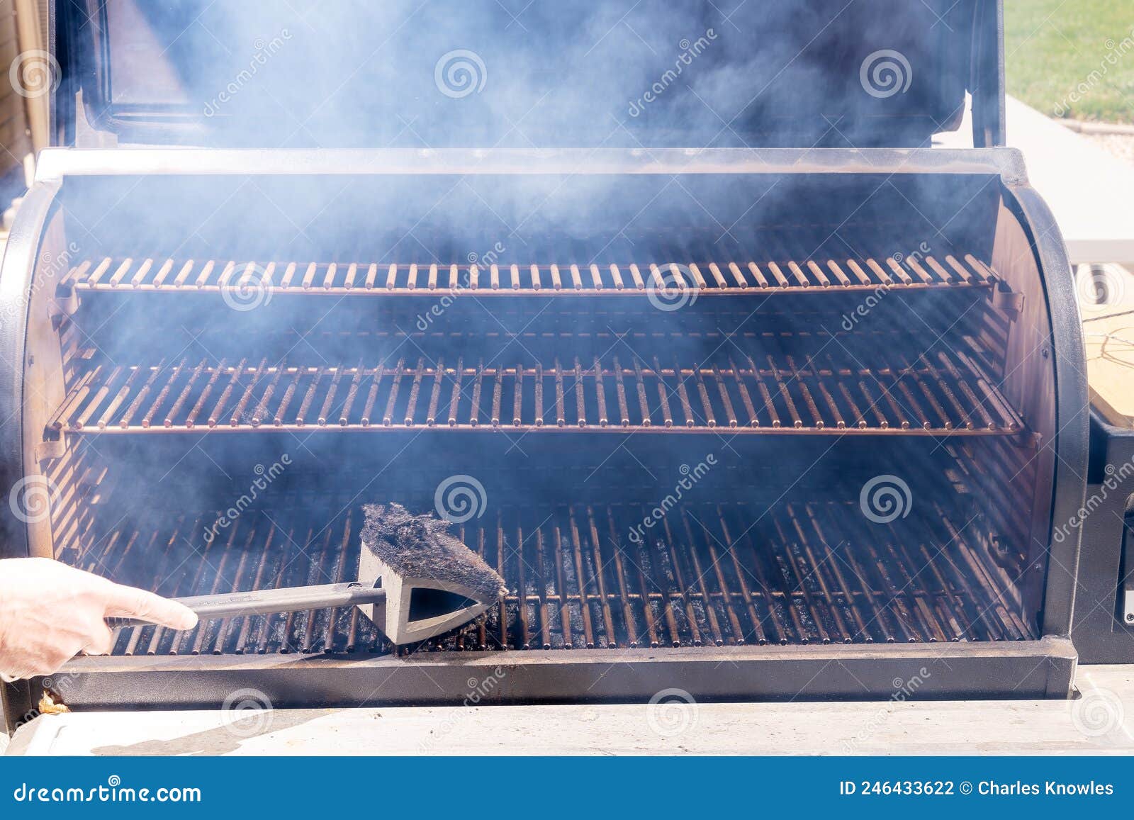 Pitmaster Uses a Brush To Clean Grill of a Smoker Stock Photo Image