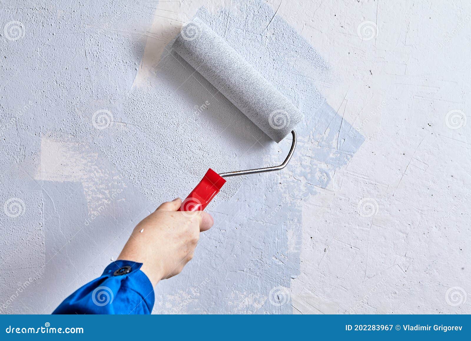 Un pittore dipinge un muro di cemento con vernice bianca, un maschio di  mano con un rullo di vernice per la verniciatura di una parete Foto stock -  Alamy
