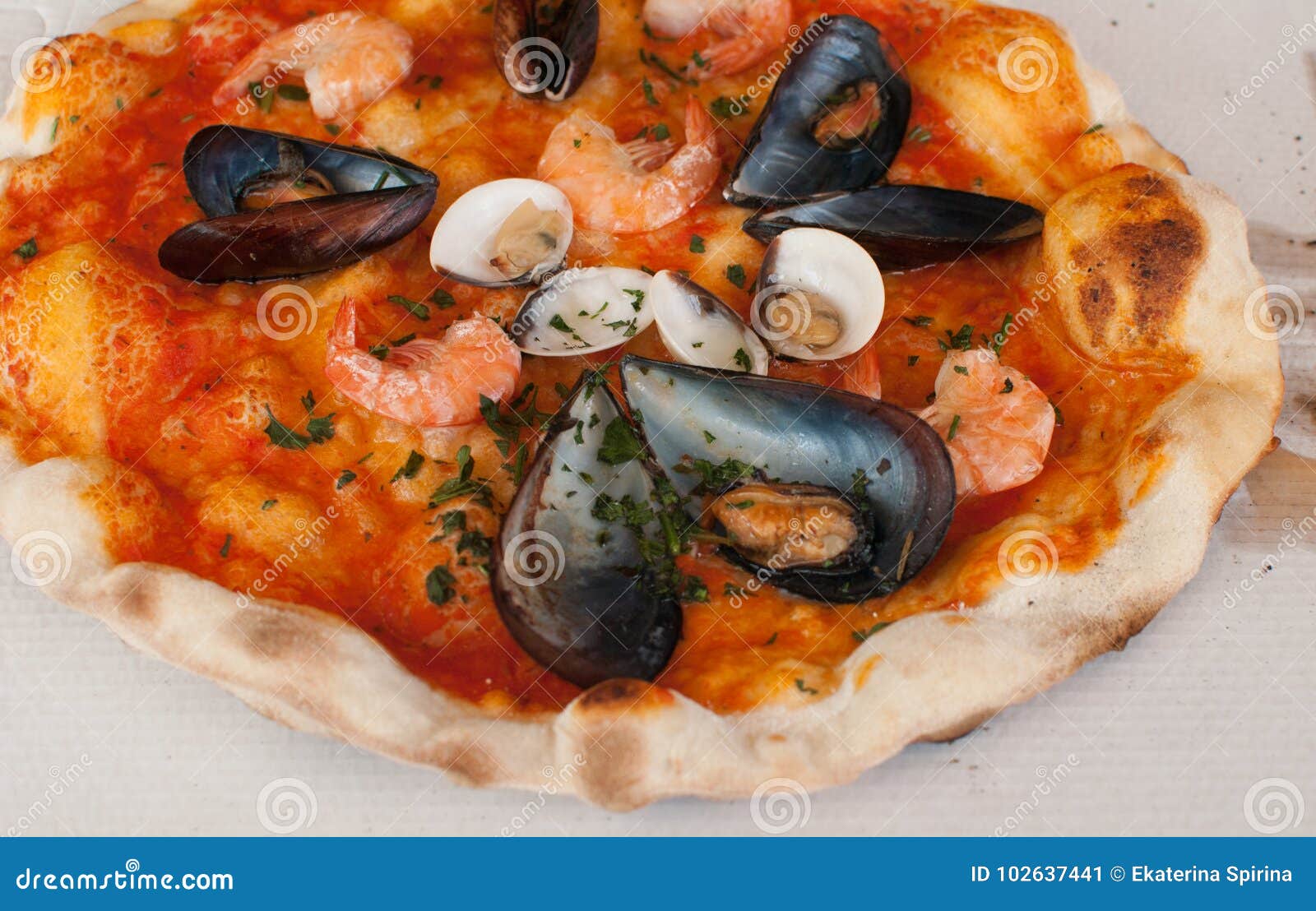 pizza frutti di mare with shrimps, open clams and mussels and basilic