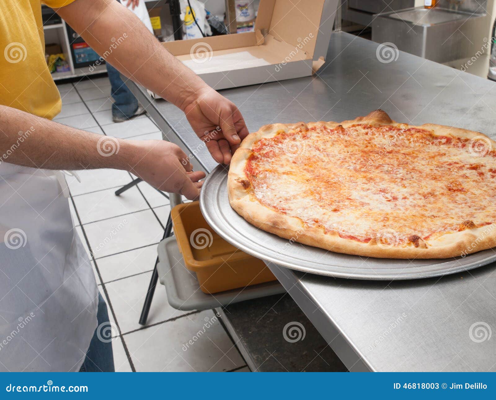 pizza maker removes a fresh pizza from the oven