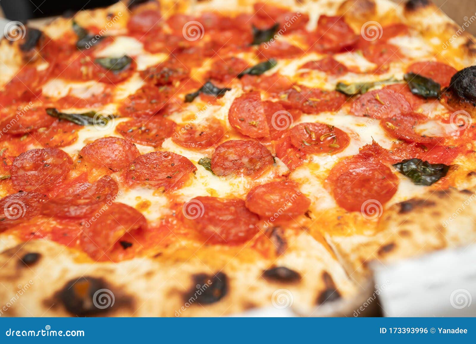 Pizza with Pepperoni Sausages, Cheese, Basil and Spices Stock Photo