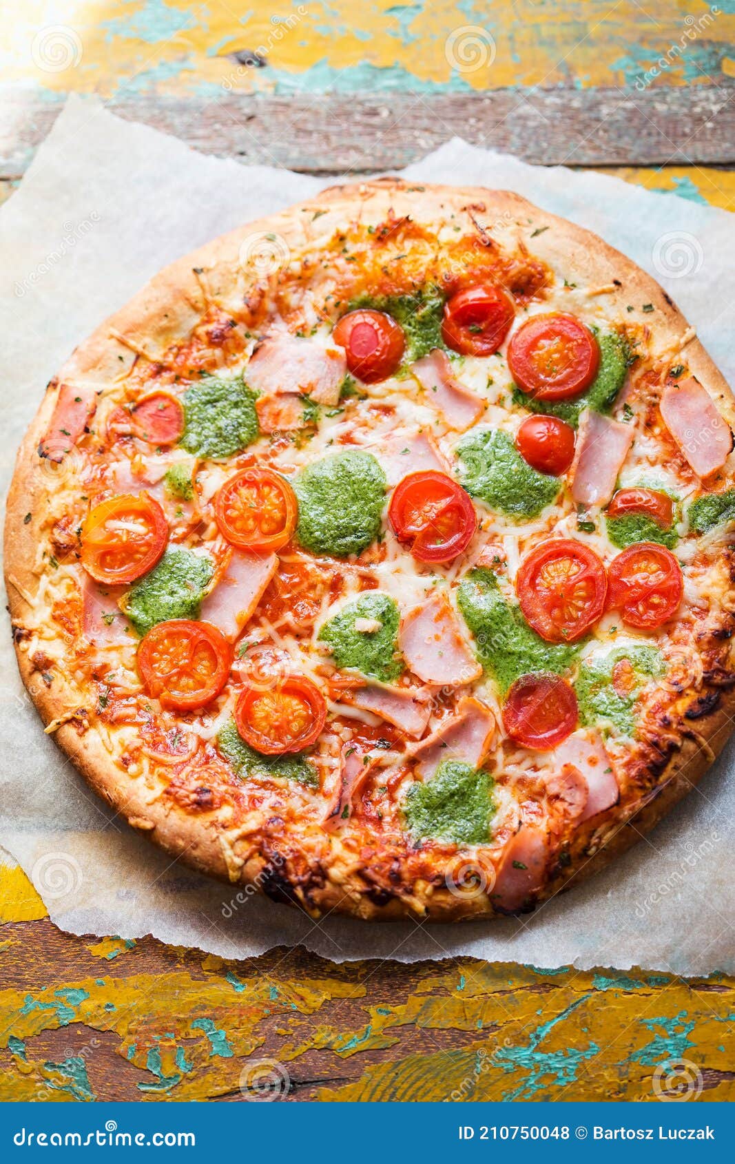Pizza with Prosciutto, Ham, Green Pesto and Tomatoes Stock Photo