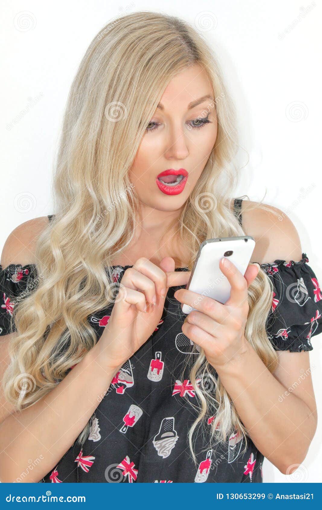 Piękna młoda blondynka z długie włosy, patrzejący zaskakujący przy telefonem komórkowym na białym tle,