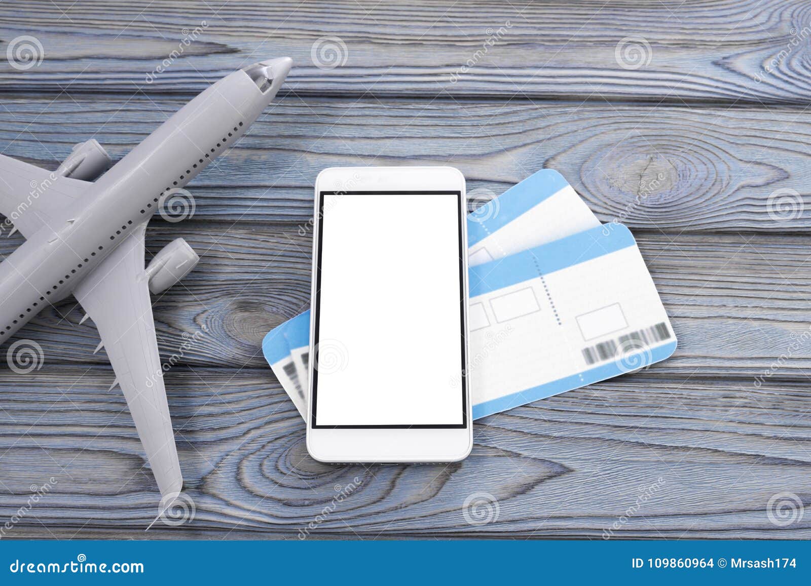 plane, tickets, smartphone with a white screen on a wooden background.