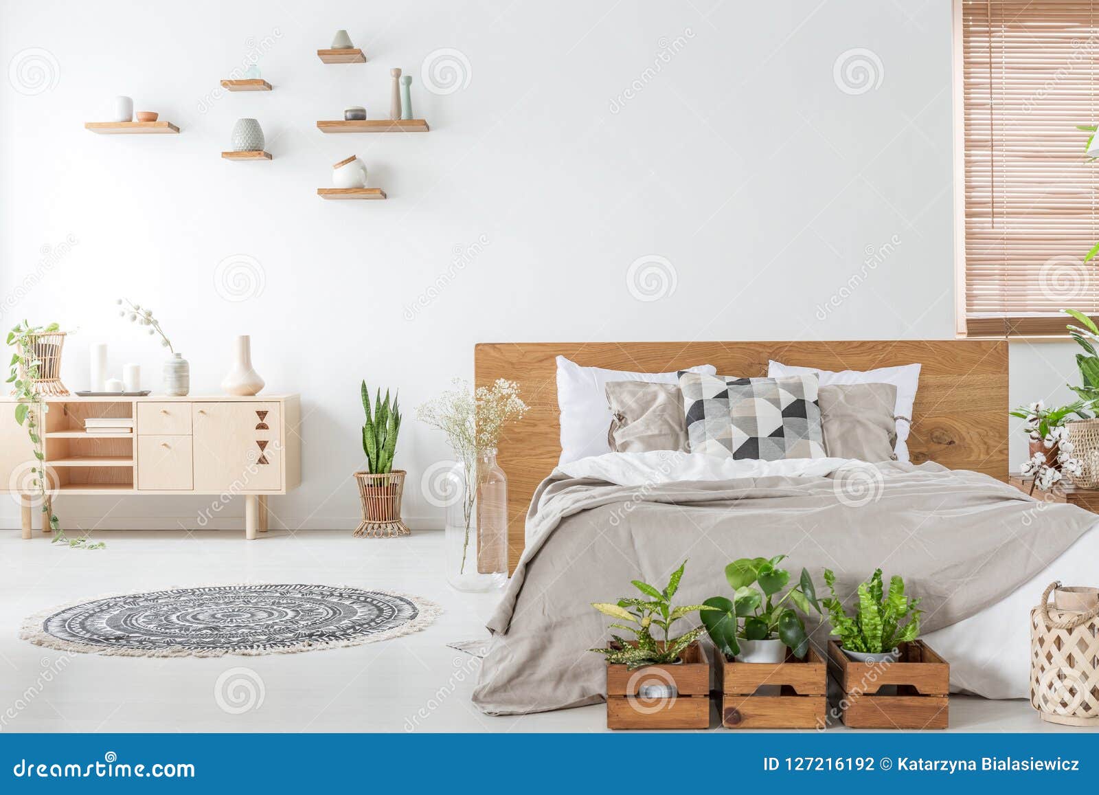 Plants In Front Of Wooden Bed In White Bedroom Interior With Rug