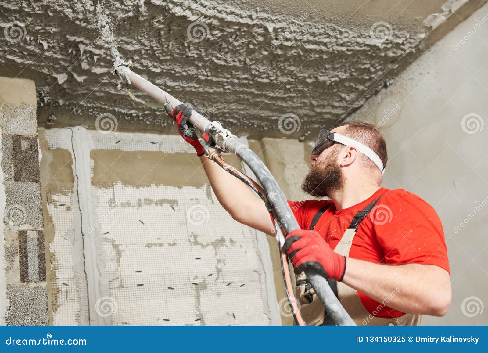 Plasterer Spraying Plastering Mortar On Ceiling With Sprayer