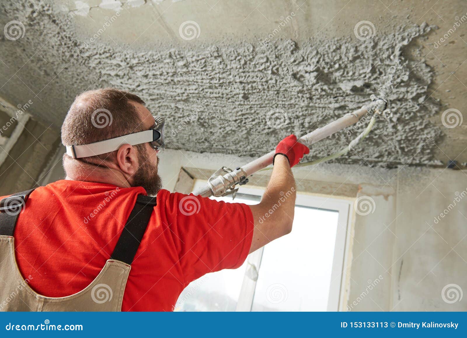 Plasterer Using Sprayer Machine Putting Plaster Mortar on Ceiling Stock