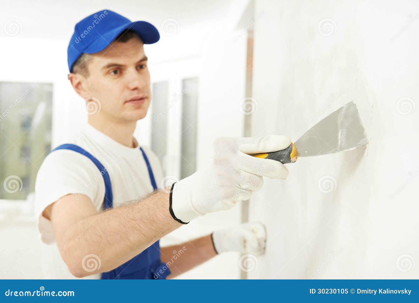 plasterer with putty knife at wall filling