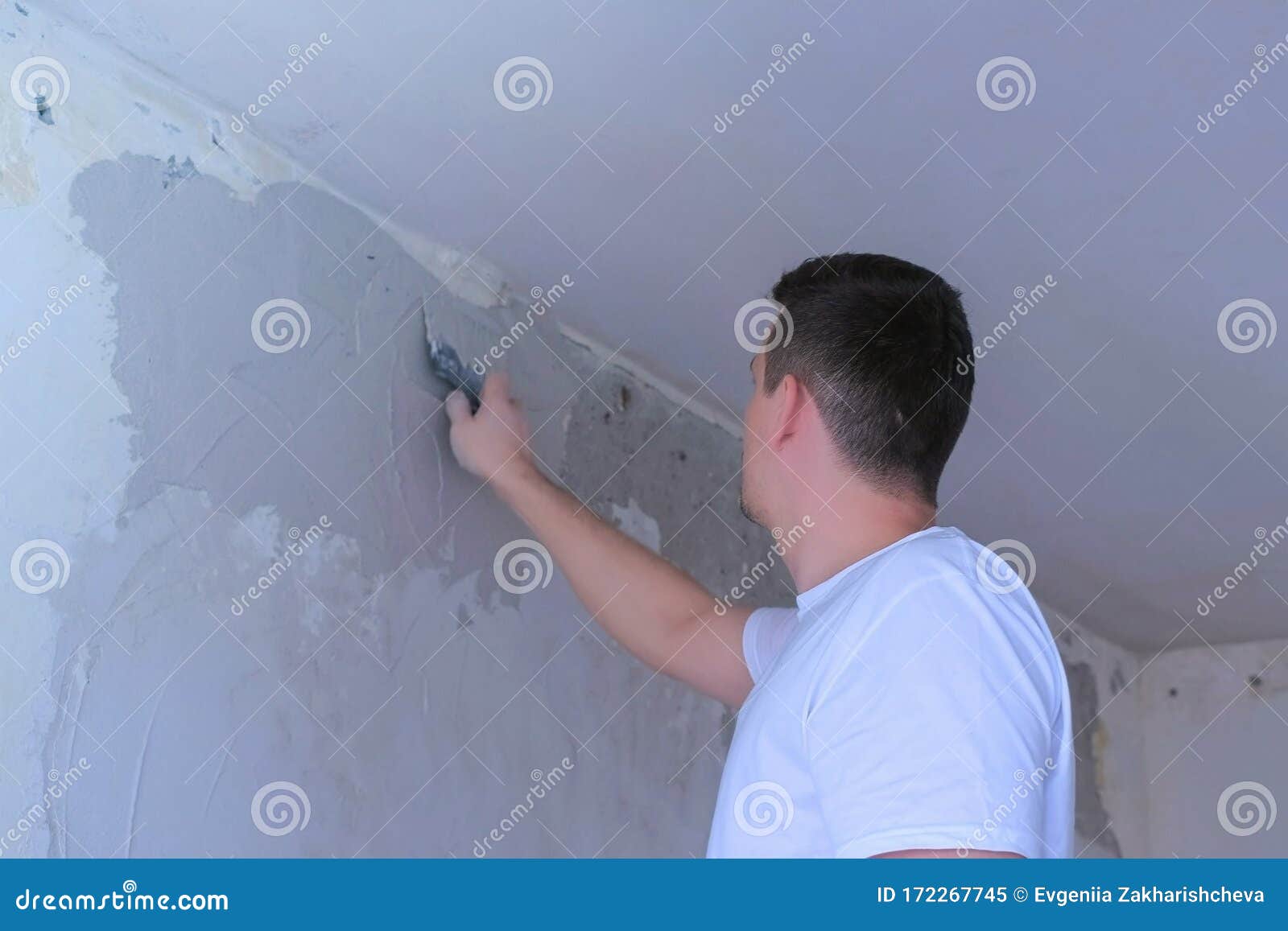 Plasterer Man Spackling Wall with Putty Plaster Aligning Wall Using