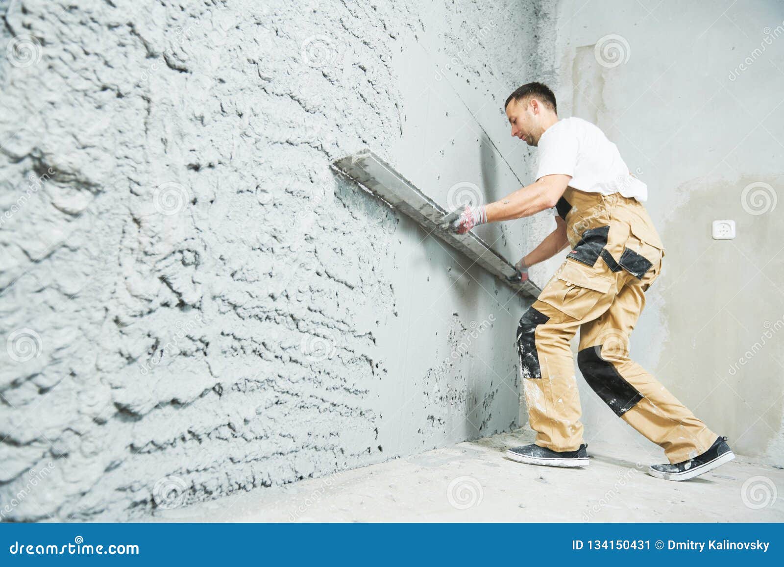 plasterer using screeder smoothing putty plaster mortar on wall