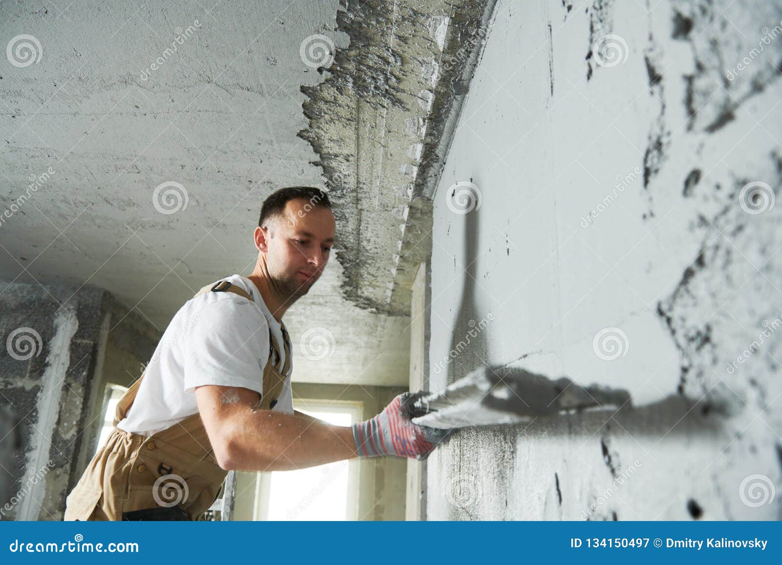 plasterer using screeder smoothing putty plaster mortar on wall