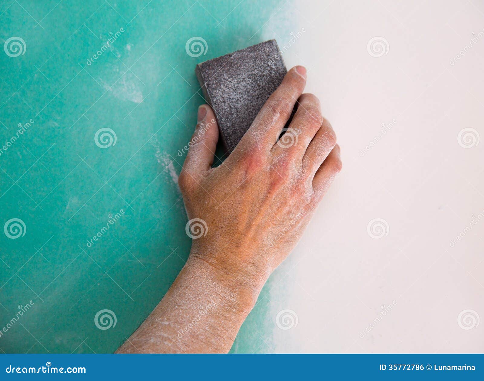plastering man hand sanding the plaste in drywall seam