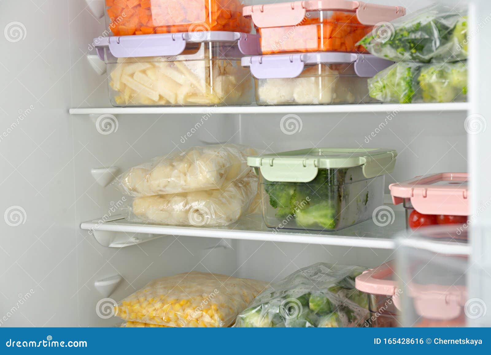 Plastic Bags and Containers with Frozen Vegetables in Refrigerator