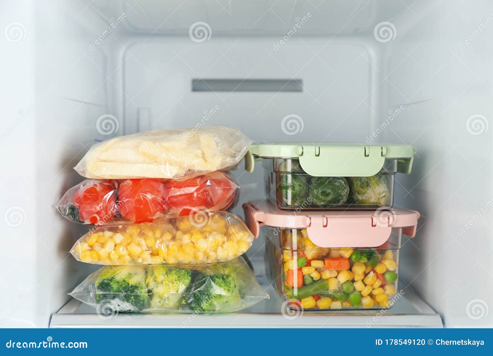 Plastic Bags and Containers with Frozen Vegetables in Refrigerator