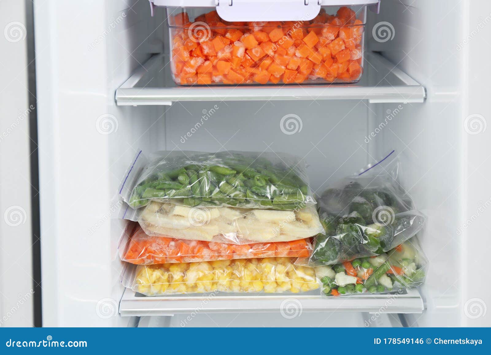 Plastic Bags and Containers with Frozen Vegetables in Refrigerator