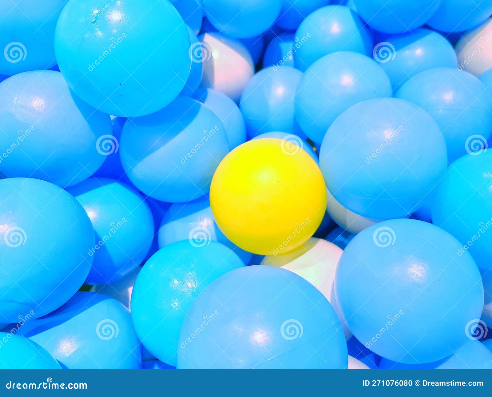 Yellow Plastic Ball among a Lot of Blue Plastic Ball Stock Photo