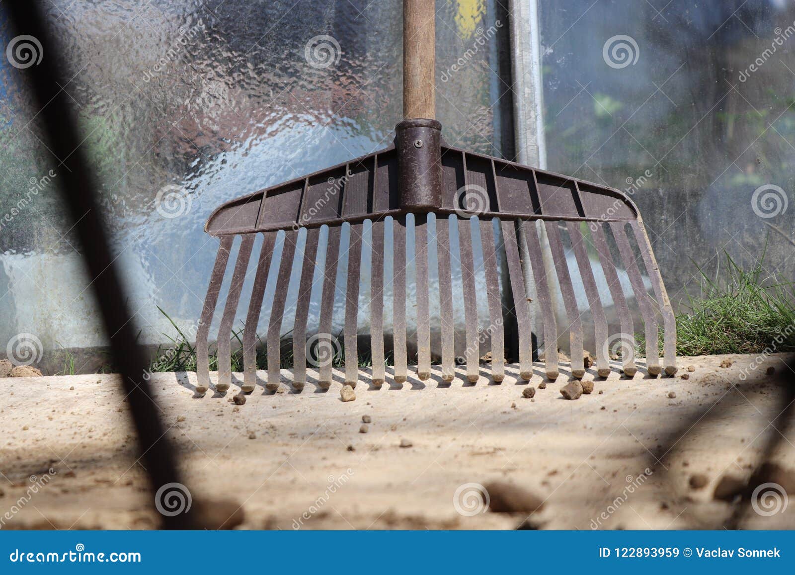 A Plastic Brown Rake Leaning Against Greenhouse. Also with Small Stones ...