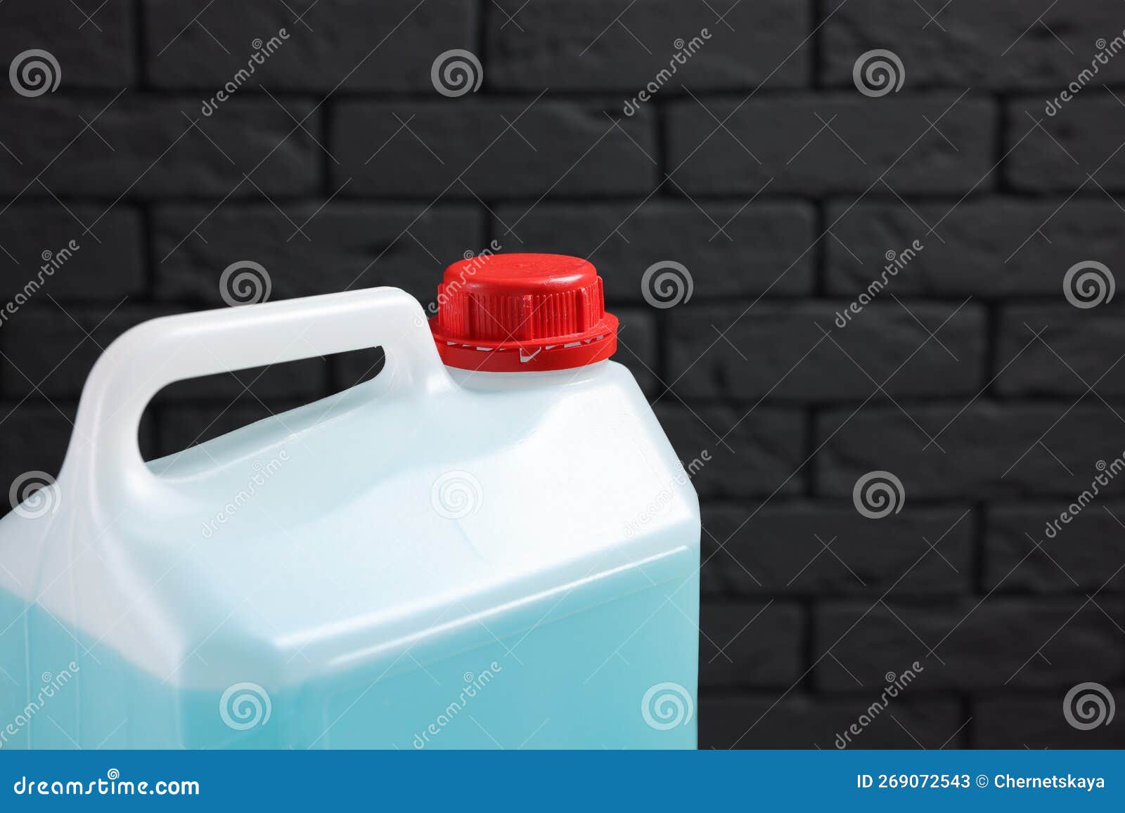 Plastic Canister with Blue Liquid Against Dark Brick Wall, Closeup