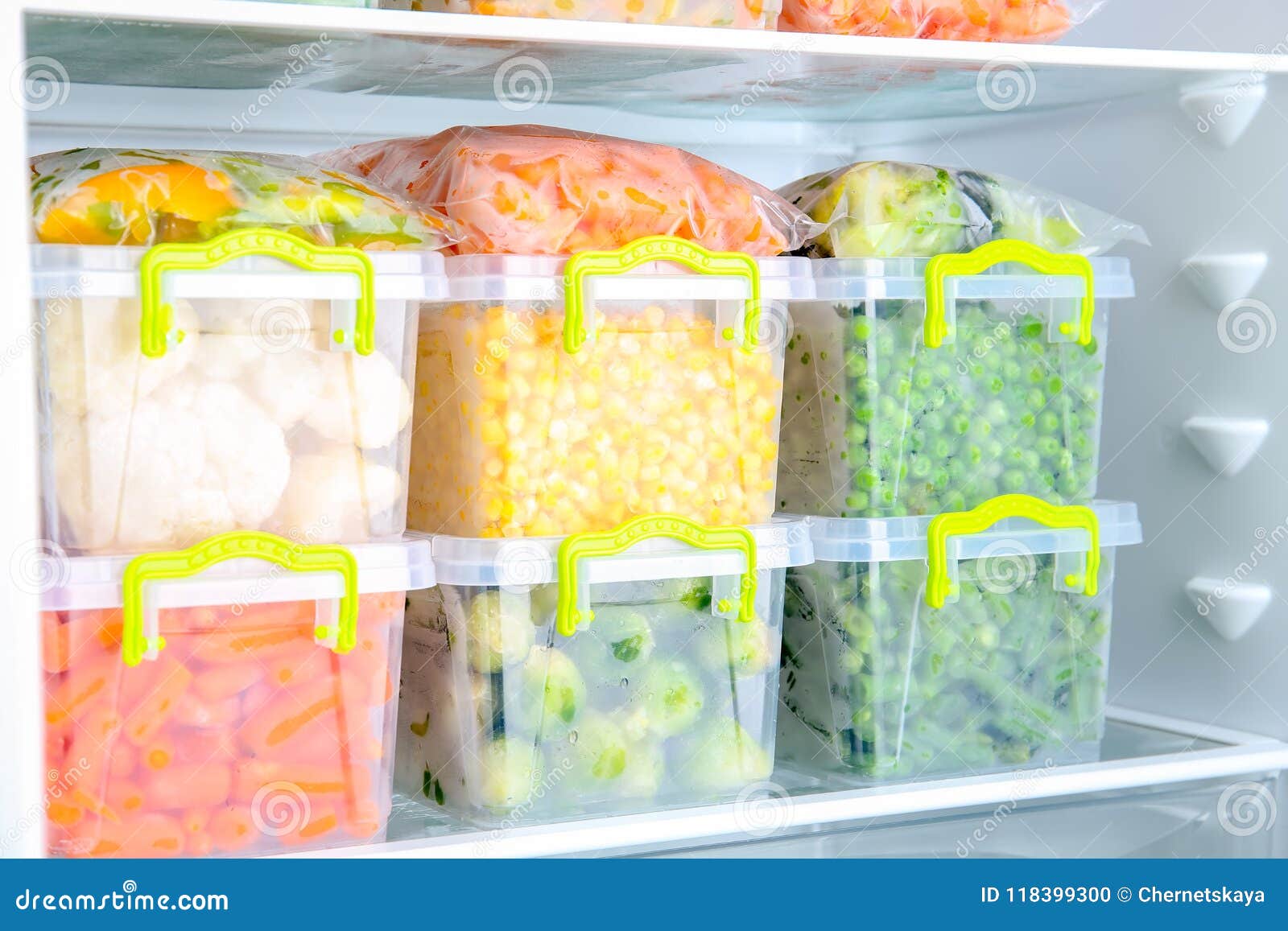 plastic containers with deep frozen vegetables in refrigerator