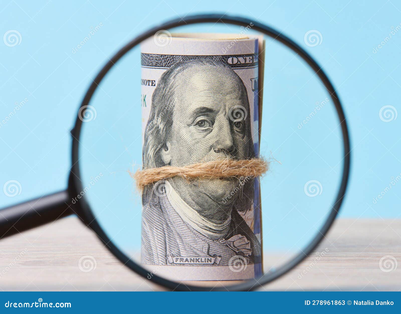 Plastic Magnifying Glass and Bound Roll of American Dollars on Blue